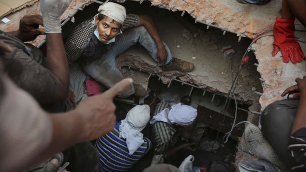Rescuers descend into holes cut in the concrete as they search for survivors.