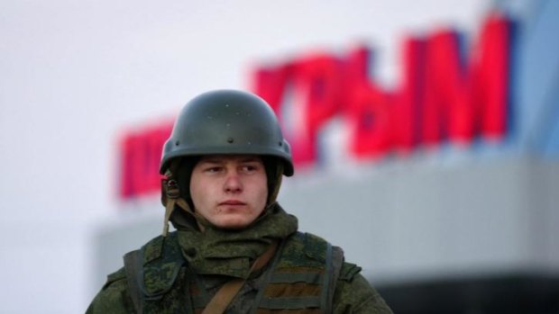An armed man, believed to be a Russian soldier, stands guard in the Crimean town of Kerch. 