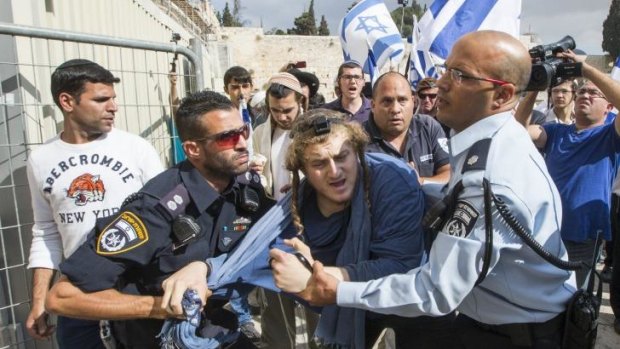 Israeli police wrestle with a far-right religious Jew trying to force his way into the al-Aqsa Mosque compound, sacred to Jews as the site of the ancient Temple.