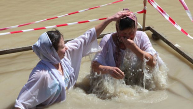 Baptism of danger... Orthodox Christian pilgrims immerse themselves in the River Jordan at Easter.