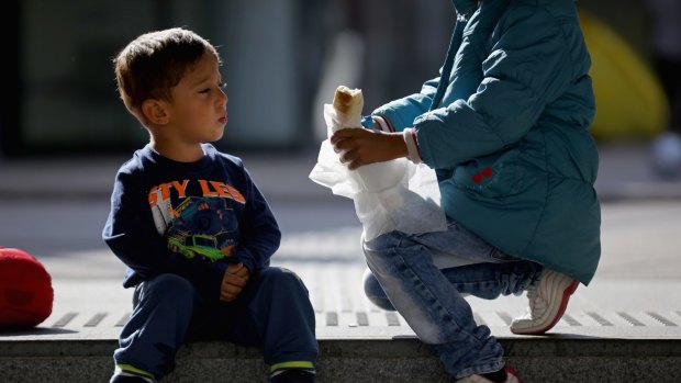 A young Syrian boy is offered food by another child as migrants wait to board a train at Keleti station in central Budapest.