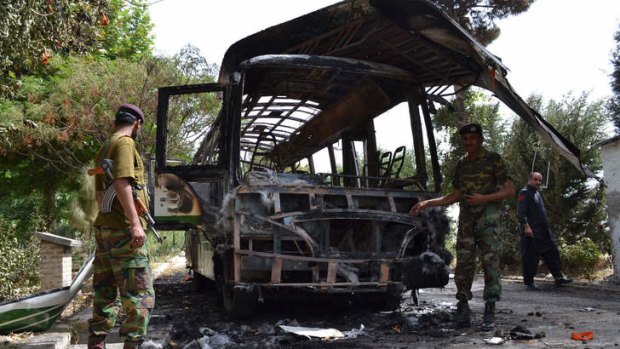 Pakistani security personnel inspect the burnt student bus a day after it was destroyed by a bomb attack, in Quetta on June 16, 2013 that killed female students.