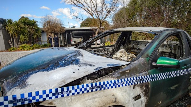 Police examine a property in Kambah after shots were fired and vehicles set alight on Friday morning in what police are describing as the latest incident in an ongoing bikie feud. Photo: Sitthixay Ditthavong