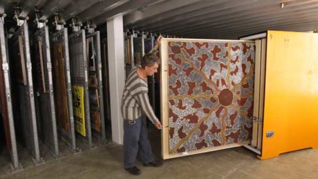 Conservator Mark Henderson packs paintings from the Papunya exhibition, including Honey Ant Hunt by Tim Leura Tjapaltarni.