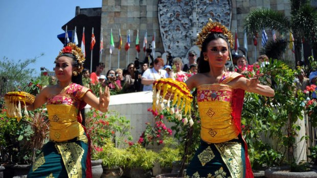 Threat ... Balinese women perform a traditional dance as tourists visit the monument in Kuta for the 2002 Bali bombing victims.