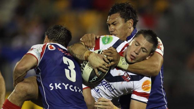 Shaun Kenny-Dowall of the Roosters is hit hard by Shaun Berrigan and Elijah Taylor of the Warriors.