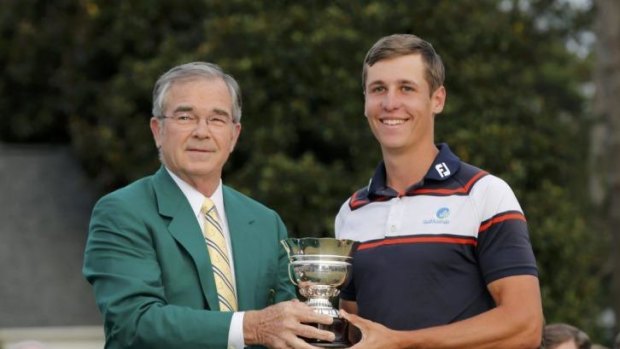 Augusta National Golf Club chairman Billy Payne (L) presents the trophy for low amateur to Australia's Oliver Goss.