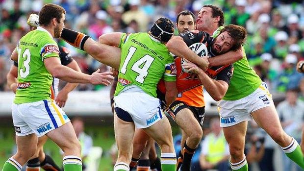 Wests Tigers' Aaron Woods is tackled by the Raiders' defence.