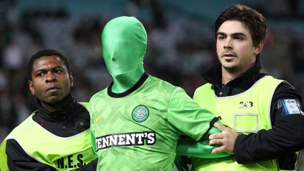 Green pest ... a fan is escorted from the pitch last night.