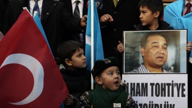 Ethnic tension: Uighur children in Turkey hold a picture of Ilham Tohti, the economist detained in Beijing.