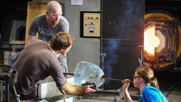 Glass artists Andrea Fiebig, right, uses a soffieta to blow air and expand the glass with Andy Baldwin and Brian Corr, rear.