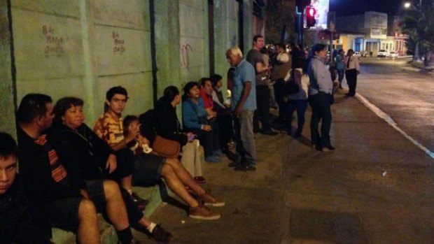 Locals sit on the street following a tsunami alert after a powerful 8.0-magnitude earthquake.