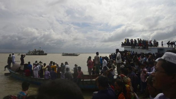 Crowds gather near the river bank where the ferry capsized.