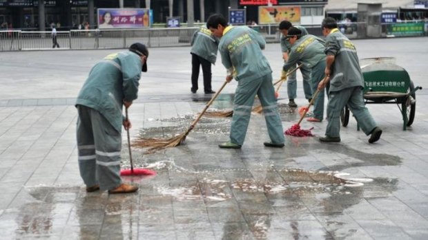 Workers clean the blood stains at the scene of a knife attack on the square of Guangzhou railway station in Guangzhou, in southern China's Guangdong province.  Six people were wounded in a knife attack.
