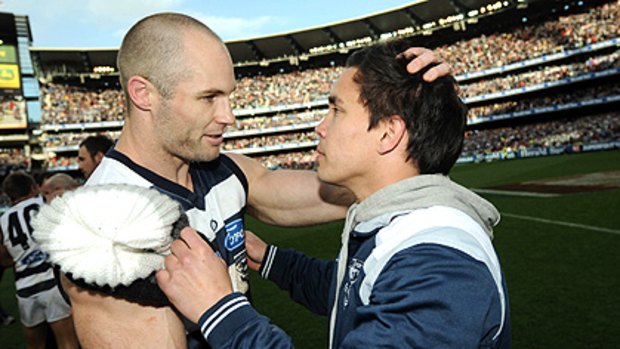 Mathew Stokes, who missed last year’s grand final, is consoled by Cats skipper Tom Harley after Geelong’s victory.