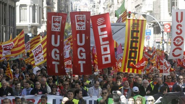 People hold banners and placards as they march during a protest against government austerity measures in Barcelona The signs are of union trades CCOO (The Workers' Commissions) and UGT (General Union of Workers).