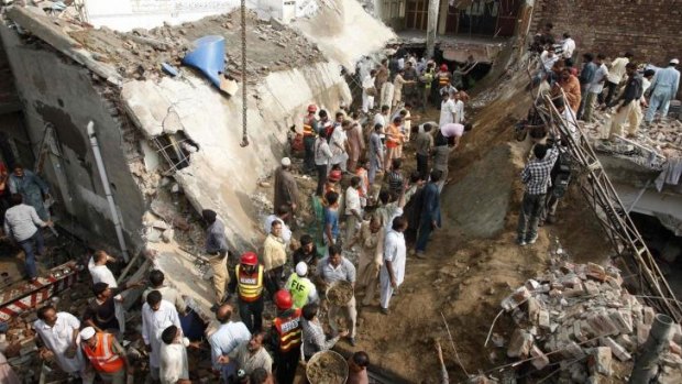Residents and rescue workers gather at the site of a mosque, after its roof collapsed, in Lahore, trapping at least 25 and killing nine.