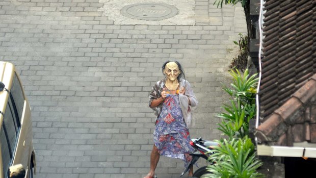 Michael Corby pranks the media by wearing a dress and mask.