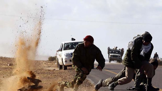 Making a run for it ... rebel fighters dodge shrapnel during heavy shelling by forces loyal to Muammar Gaddafi near Bin Jawad.