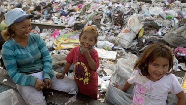 Dirty work: A scavenger with two children takes a break during her labours at the Bordo Poniente dump.
