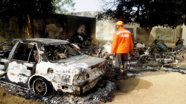 A rescue worker inspects the burnt-out wreckage of cars and motorcycles destroyed by multiple explosions in the northern Nigerian city of Kano.