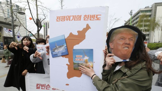 A South Korean protester holds a mask of US President Donald Trump and a Korean Peninsula map during a rally against US deployment in the region outside the US embassy in Seoul.