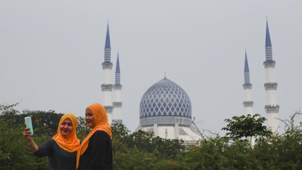 Malaysians front of the Sultan Salahuddin Abdul Aziz Shah Mosque, also known as the Blue Mosque, slightly obscured by haze in Shah Alam, Malaysia on Sunday.