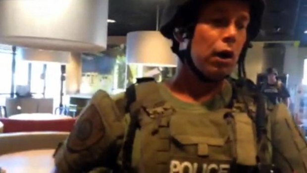 This image taken from video, provided by journalist Wesley Lowery of The Washington Post, shows a police officer confronting Lowery in a fast-food restaurant in Ferguson.