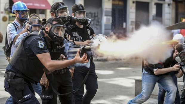 Crackdown: Police fire tear-gas as riot police spray water cannon at demonstrators who remained defiant after authorities evicted activists from an Istanbul park on Sunday.