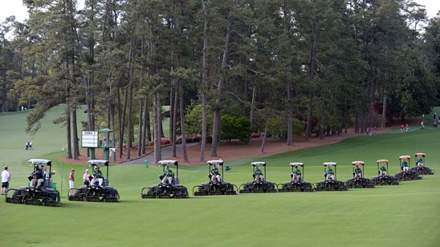 A row of lawn-mowing machines come down the fairway during a practice round at the 77th Masters.