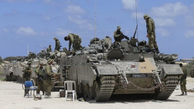 Ready to roll ... Israeli soldiers stand near tanks at the Israel-Gaza borde.