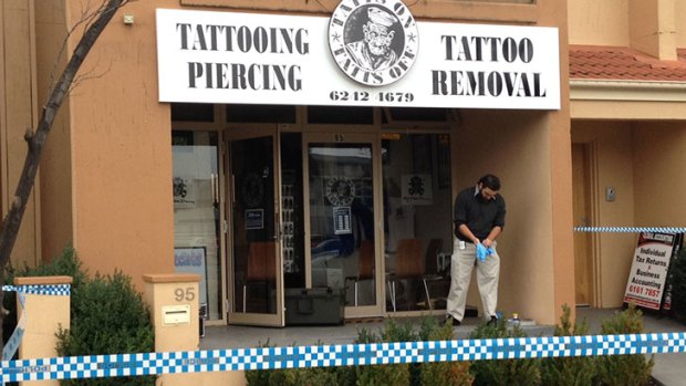 UNDER FIRE: An investigator at the Tatts On Tatts Off tattoo parlour where bullet holes were discovered in the shop front on Tuesday morning.