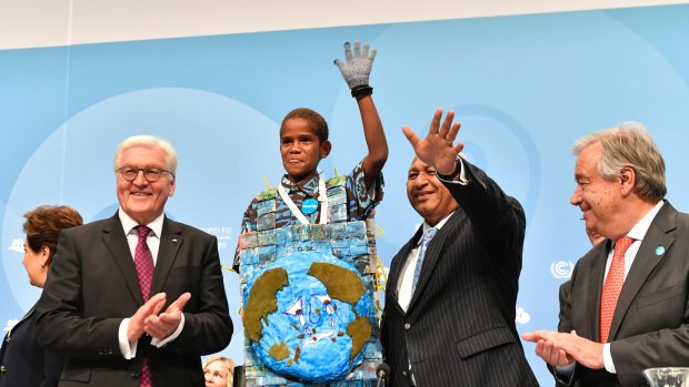 German President Frank-Walter Steinmeier, left, and UN Secretary General Antonio Guterres, right, applaud as Fiji prime minister and COP president Frank Bainimarama, second right, and a child from Fiji wave to the audience.