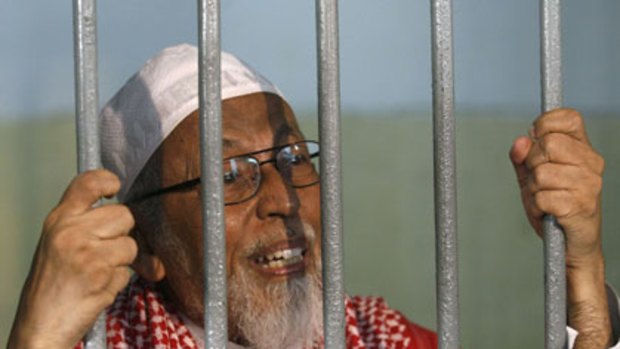 Has pleaded not guilty ... Abu Bakar Bashir talks to journalists from a cell at the court before his hearing.