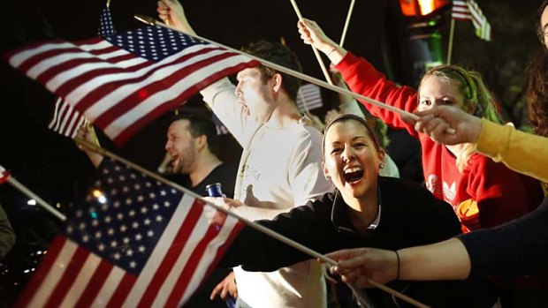 Joy: People wave U.S. flags while cheering as police drive down Arlington street in Watertown, Massachusetts.
