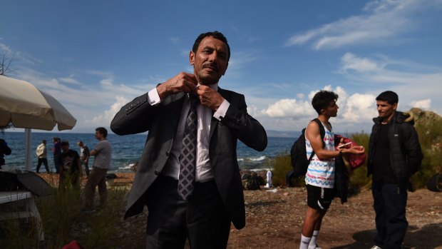 Abdullah al-Salman, from Syria, straightens his tie as he dresses in his best suit moments after arriving by rubber dinghy with about 45 other refugees from Syria, Iraq and Afghanistan at the Greek island of Lesvos  after a three-hour journey from Turkey.
