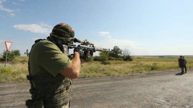 Pro-Russian rebel sniper 'Angel' looks through the scope of his gun at a checkpoint on the outskirts Shakhtersk and aims over the shoulder of locals. 