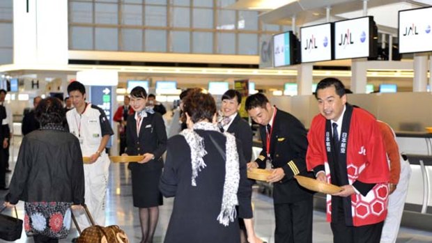 Japan Airlines president Masaru Onishi (R) greets passengers at the newly opened international terminal building of the Tokyo International Airport.