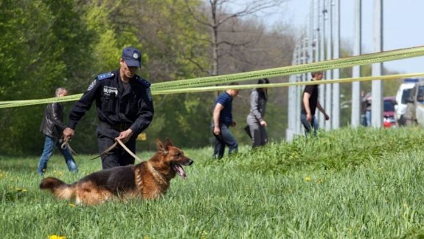 A Ukrainian policeman with a sniffer dog examines the place where mayor Gennady Kernes was shot.