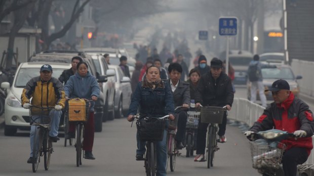 People ride on bicycles through haze in Beijing, China, earlier this year. 
