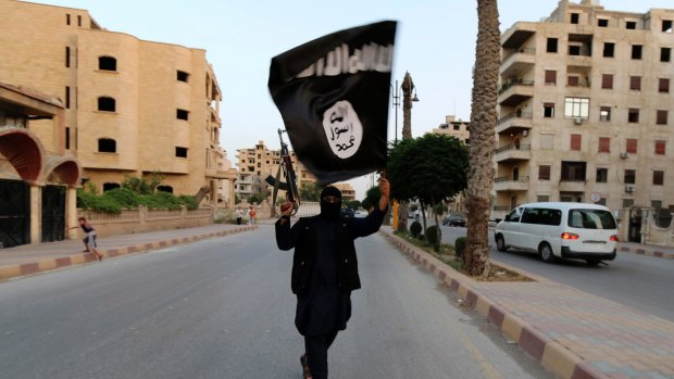 Tactical: A member loyal to the Islamic State in Iraq waves an ISIL flag in Raqqa.