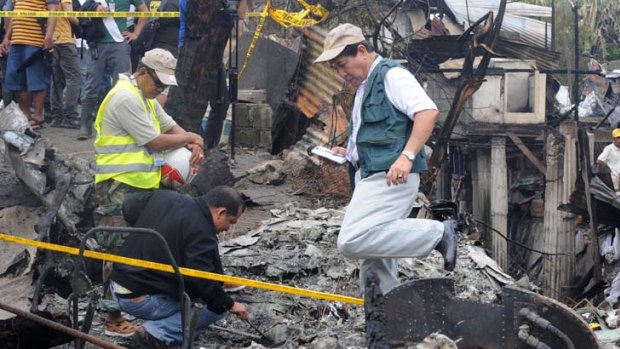 Authorities comb through the wreckage after a cargo  plane that crashed into a Manila slum killing at least 13 people.