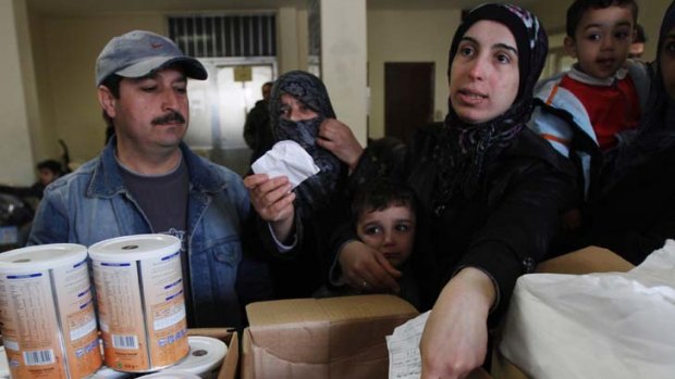 Struggling to feed their families ... a Syrian woman receives humanitarian food aid. Food is more sparse in areas where the fighting is more intense.