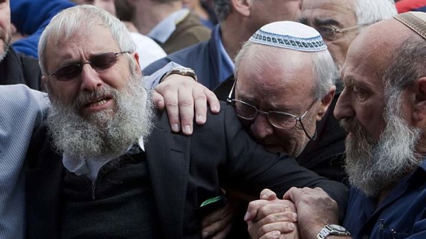 Relatives and friends mourn at the funeral of the three murdered Fogel children.