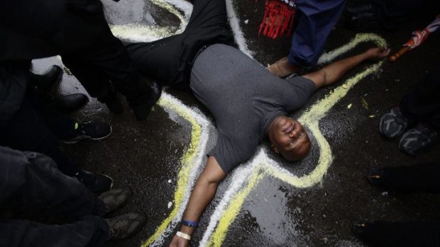 Stark message: Pastor Charles Burton has his body outlined with chalk to replicate a crime scene as he and other demonstrators protest the shooting of Michael Brown outside the Ferguson police station.
