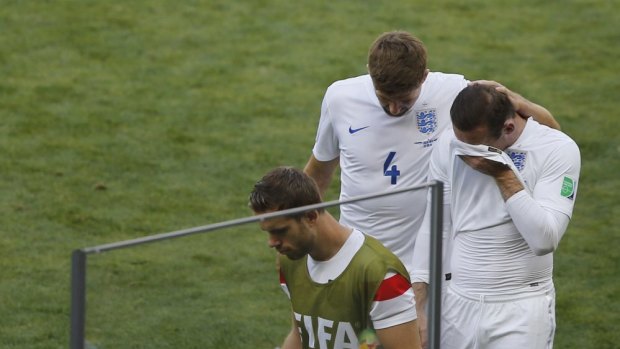 England's Wayne Rooney (10) wipes his face as he leaves the pitch with teammate Steven Gerrard .