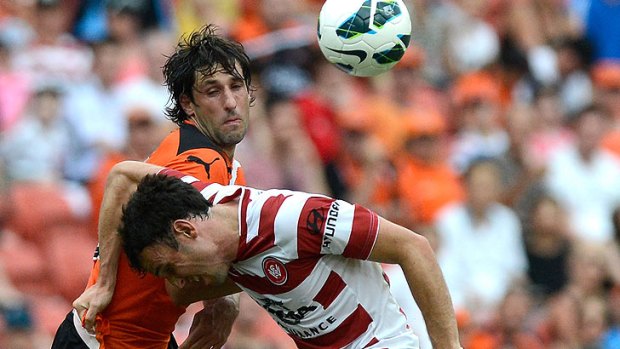 Roar midfielder Thomas Broich and Mark Bridge of the Wanderers challenge for the ball at Suncorp Stadium.
