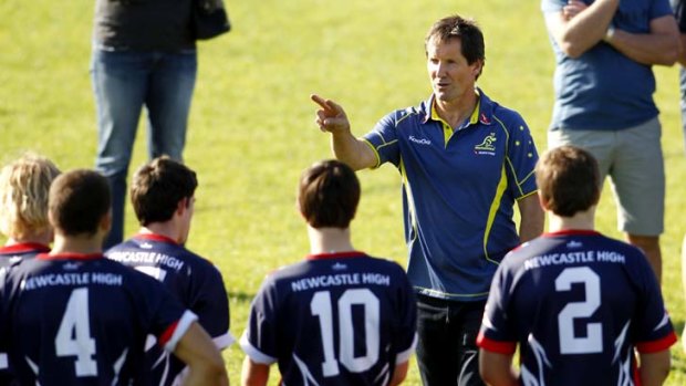 Laying down the law ... Wallabies coach Robbie Deans puts students from Newcatle High School through their places yesterday. Deans has been in touch with the injured duo of Quade Cooper and James O'Connor.