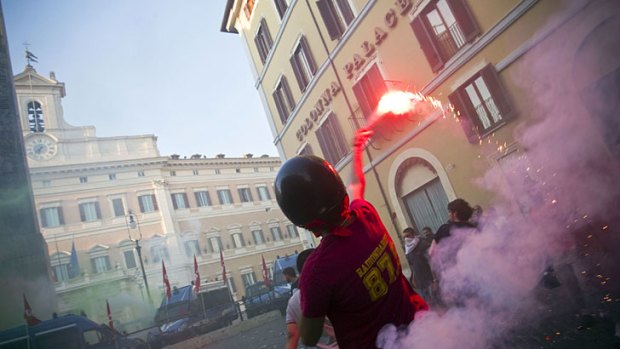 Flare up ... a protester ignites a firework outside the Italian Parliament this week as, inside, politicians voted on austerity measures.