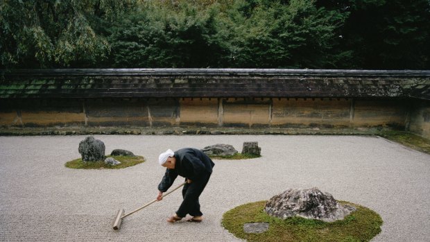 A young monk rakes the famous Japanese rock garden of  Ryoan-ji early in the morning.

